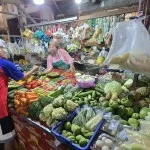 Pedagang melayani pembeli di lapak sayur pasar tradisional