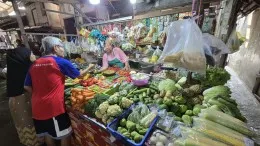 Pedagang melayani pembeli di lapak sayur pasar tradisional