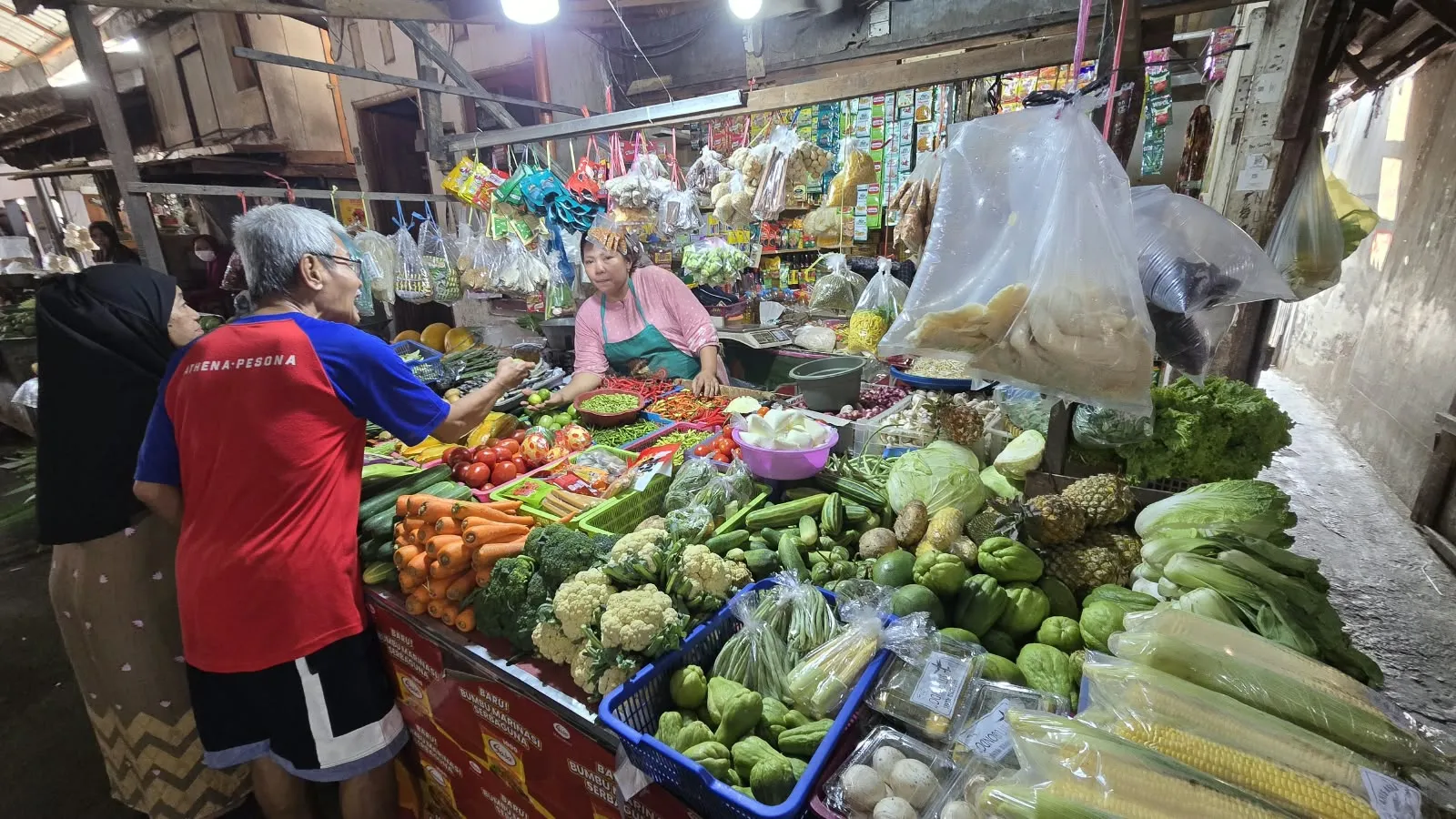 Pedagang melayani pembeli di lapak sayur pasar tradisional