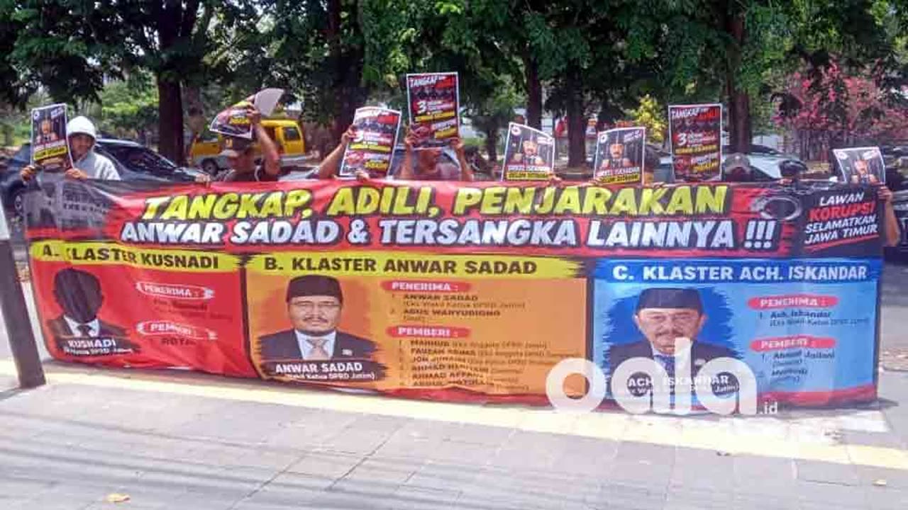 Massa membentangkan spanduk tuntutan di depan gerbang Pengadilan Tipikor Surabaya.