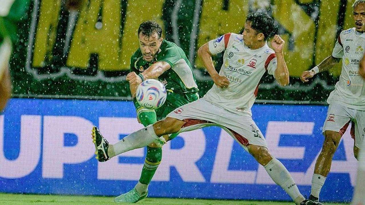 Pemain Persebaya dan Madura United berebut bola dalam Derby Suramadu di Stadion Gelora Bung Tomo Surabaya yang diguyur hujan.