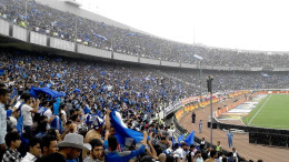 Suporter memadati tribun stadion sepak bola.