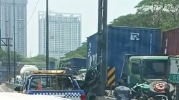 Truk kontainer biru KMTC Line dan truk kontainer merah tex yang terlibat kecelakaan di Tol Satelit KM 7.600 arah Dupak, Surabaya, dengan mobil derek di lokasi